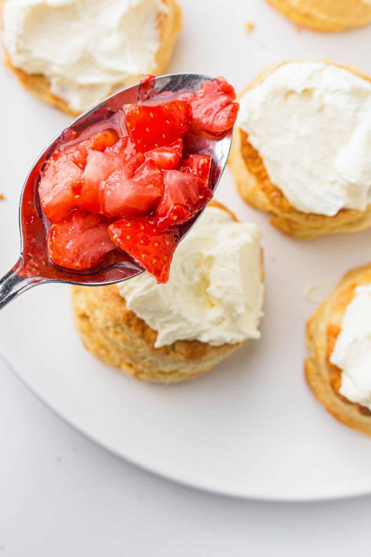 Biscuits topped with whipped cream and spooned strawberries.