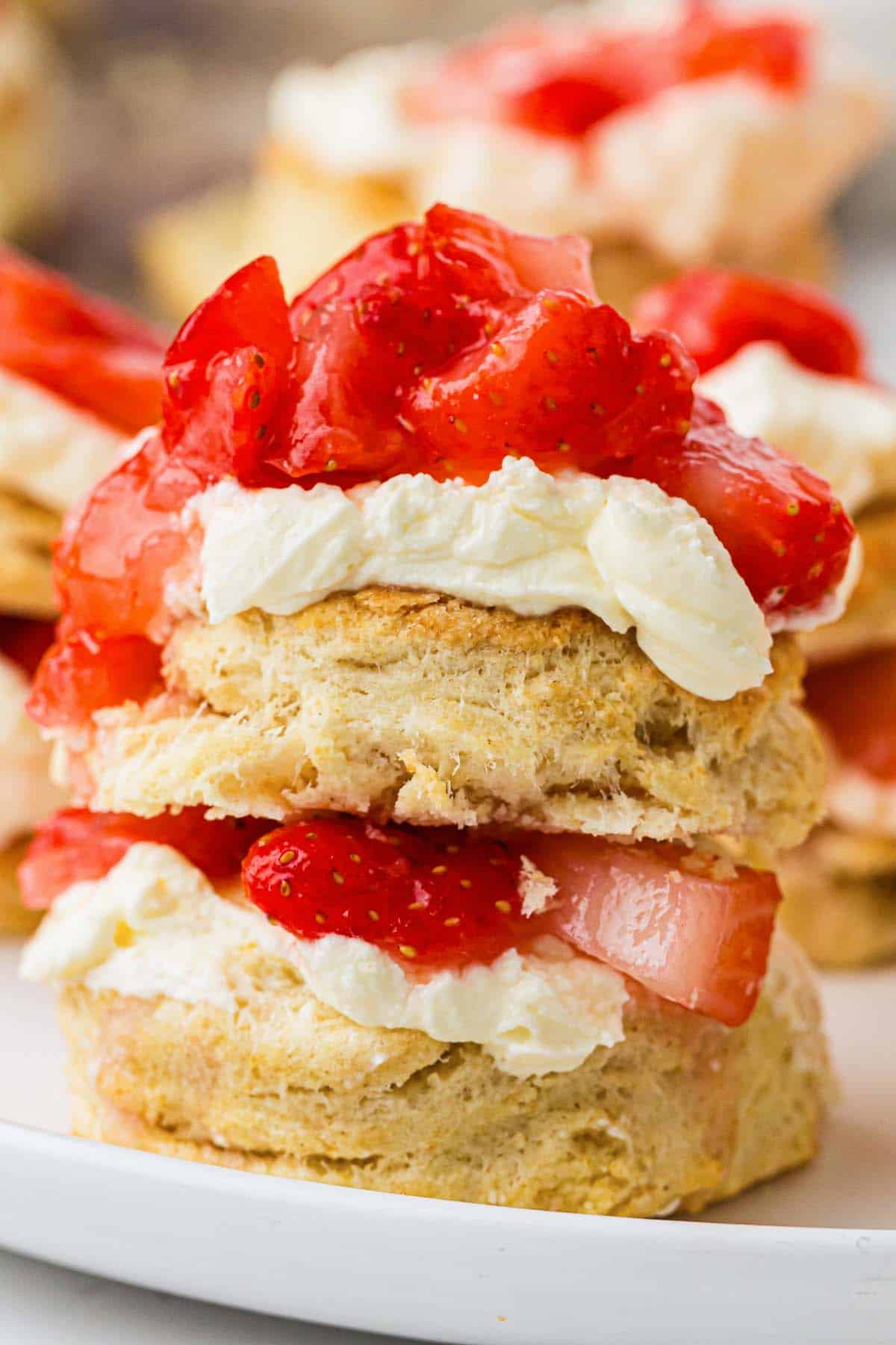 Strawberry shortcake biscuit layered with whipped cream and fresh strawberries on a plate.