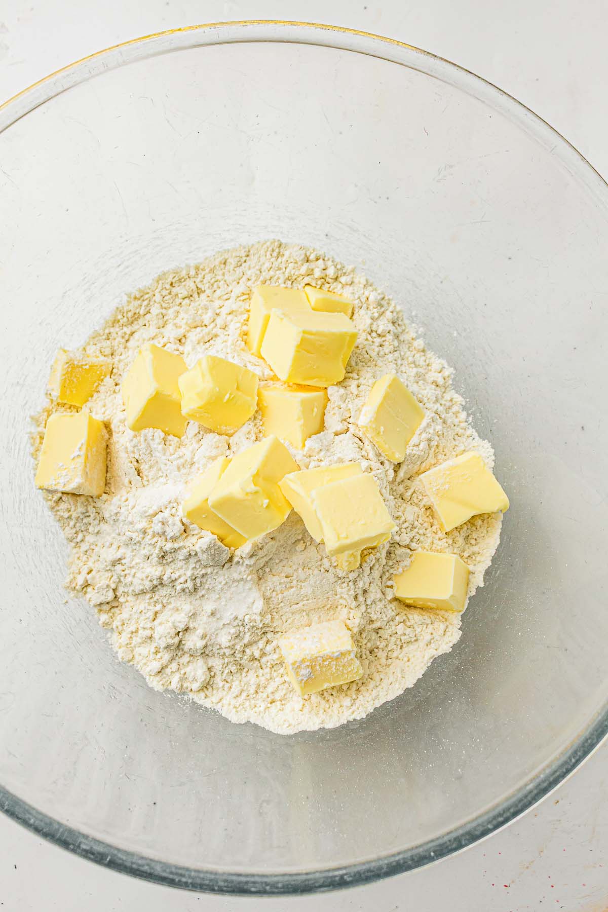 Flour topped with cubed butter in a glass bowl.