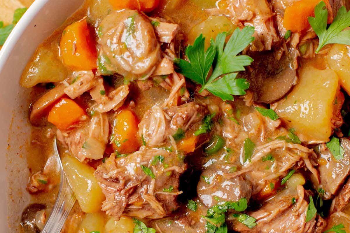 Slow cooker beef stew with potatoes, carrots, mushrooms, and herbs.