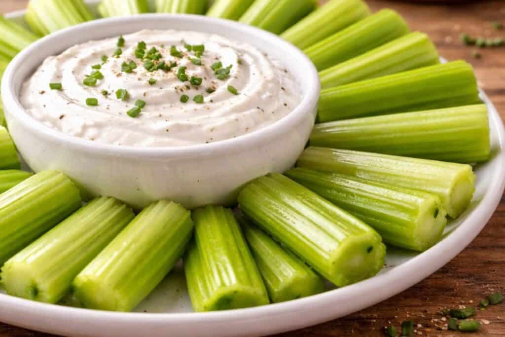 Celery sticks arranged around creamy dip