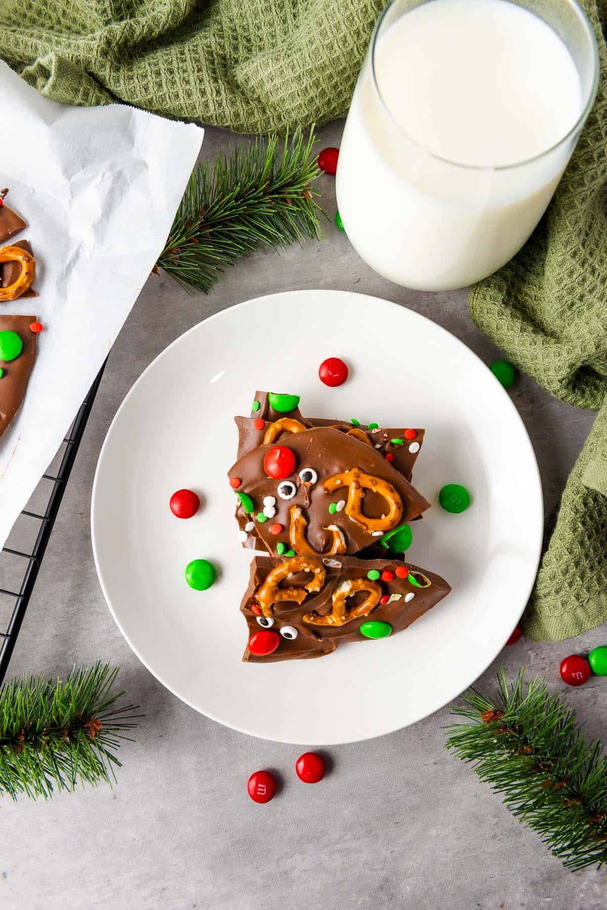 Chocolate bark pieces on a plate with milk and holiday greenery.
