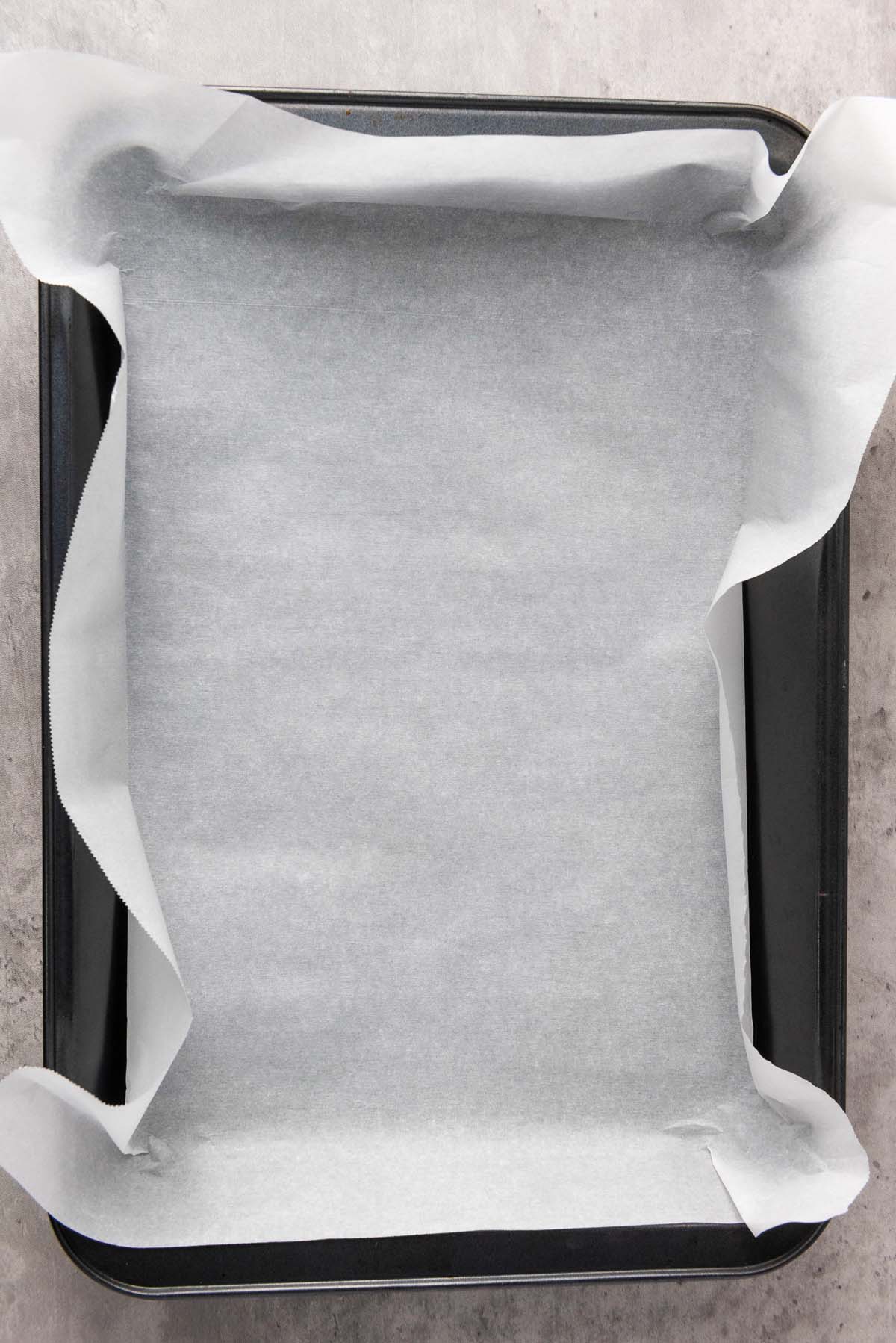 Baking pan lined with parchment paper on a countertop.