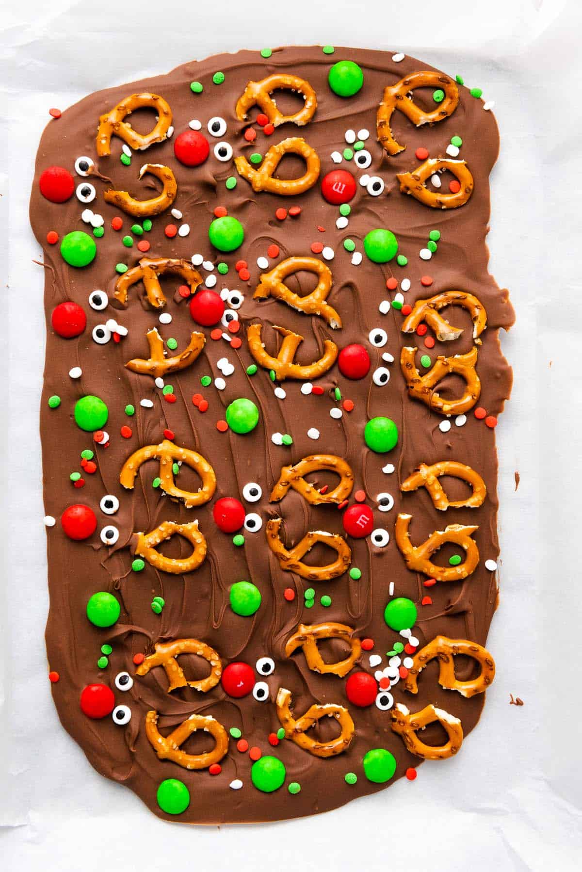 Christmas chocolate bark with pretzels, red and green candies, and sprinkles.