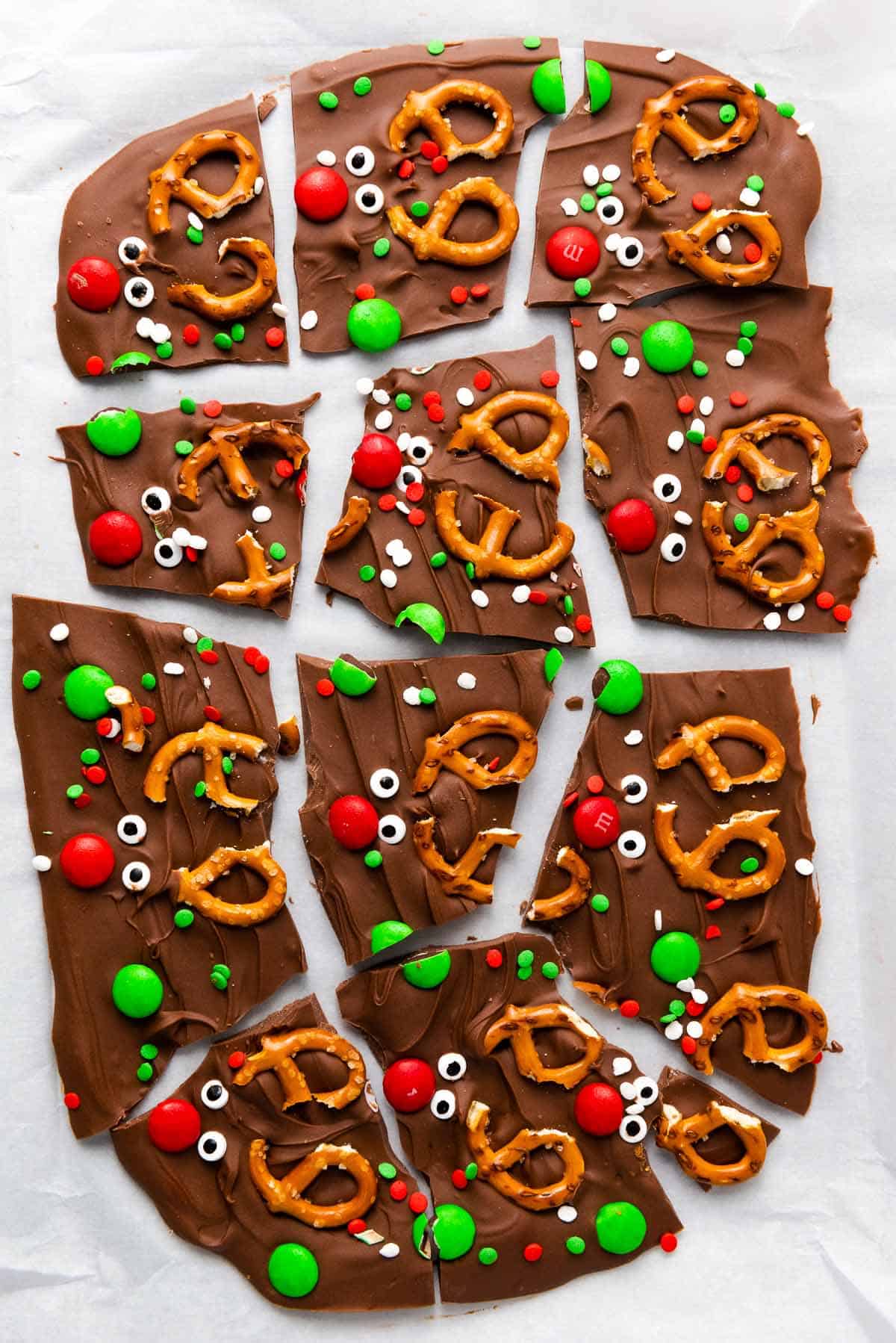Broken pieces of Christmas chocolate bark with pretzels and candies.