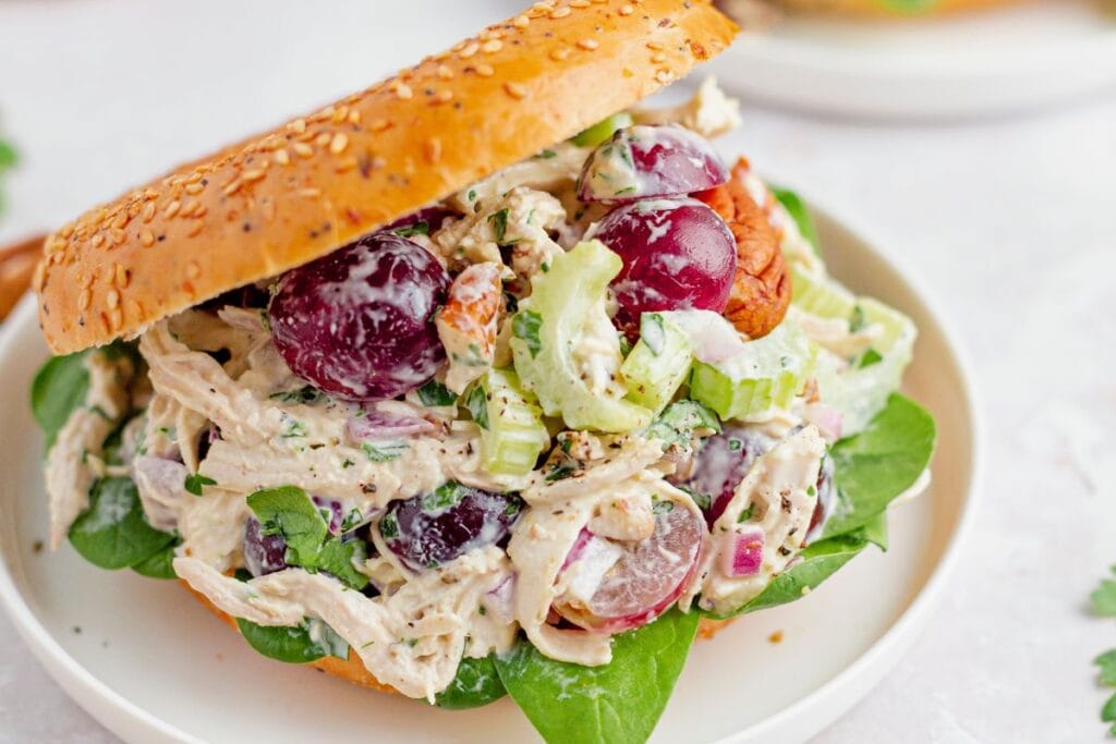Chicken salad sandwich with grapes and pecans on leafy greens