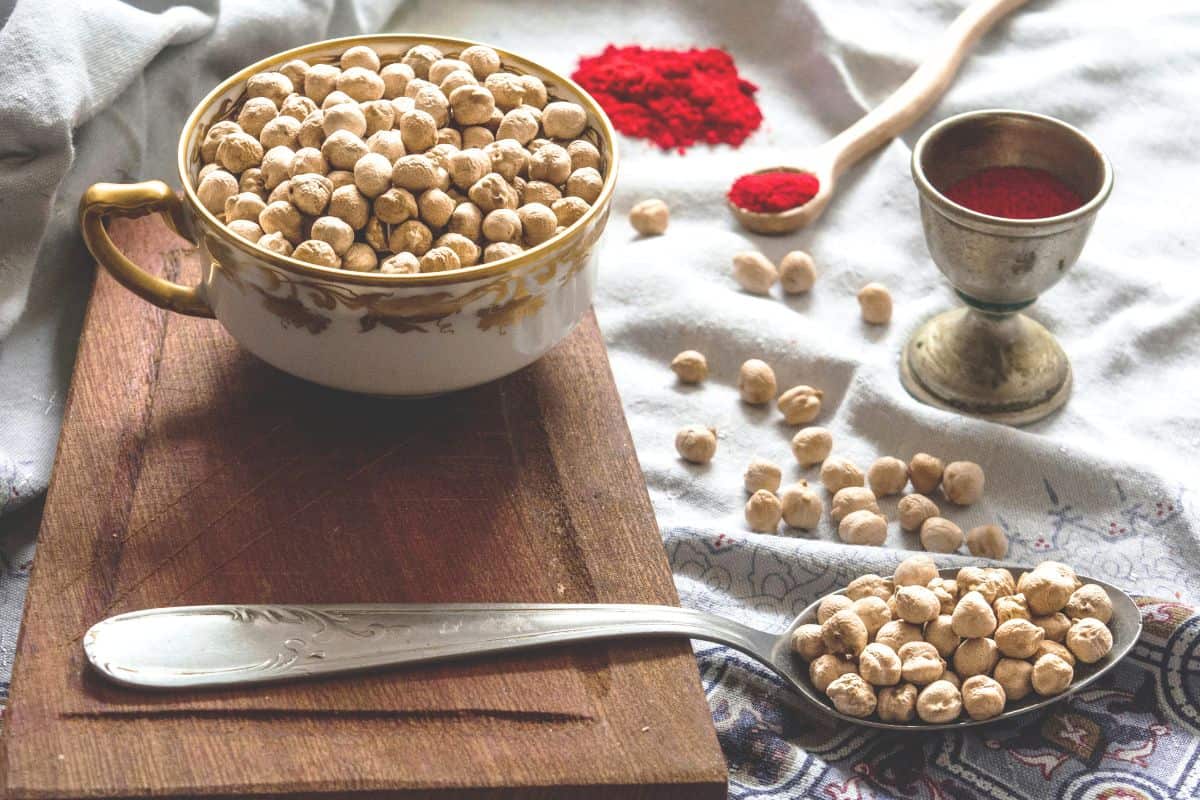 Bowl of dried chickpeas with spices and spoon on rustic kitchen setup