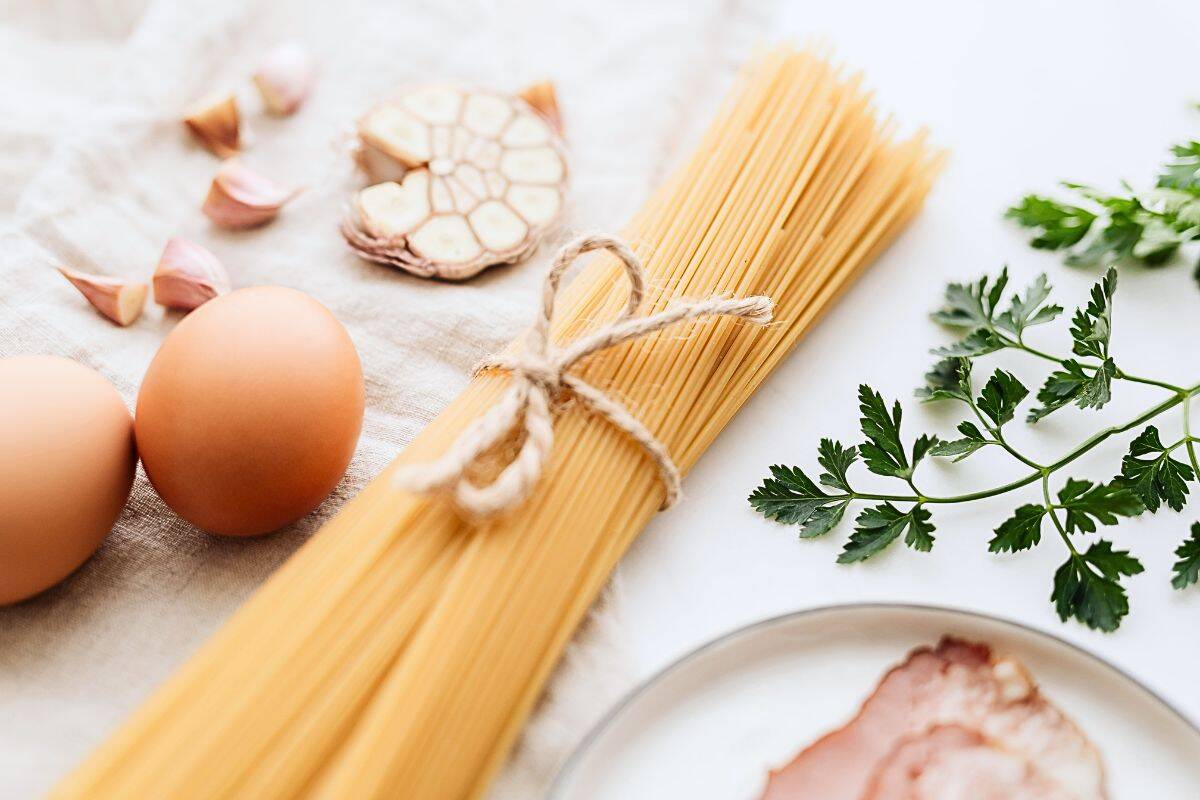 Bundle of dry spaghetti with eggs, garlic, and parsley on kitchen cloth