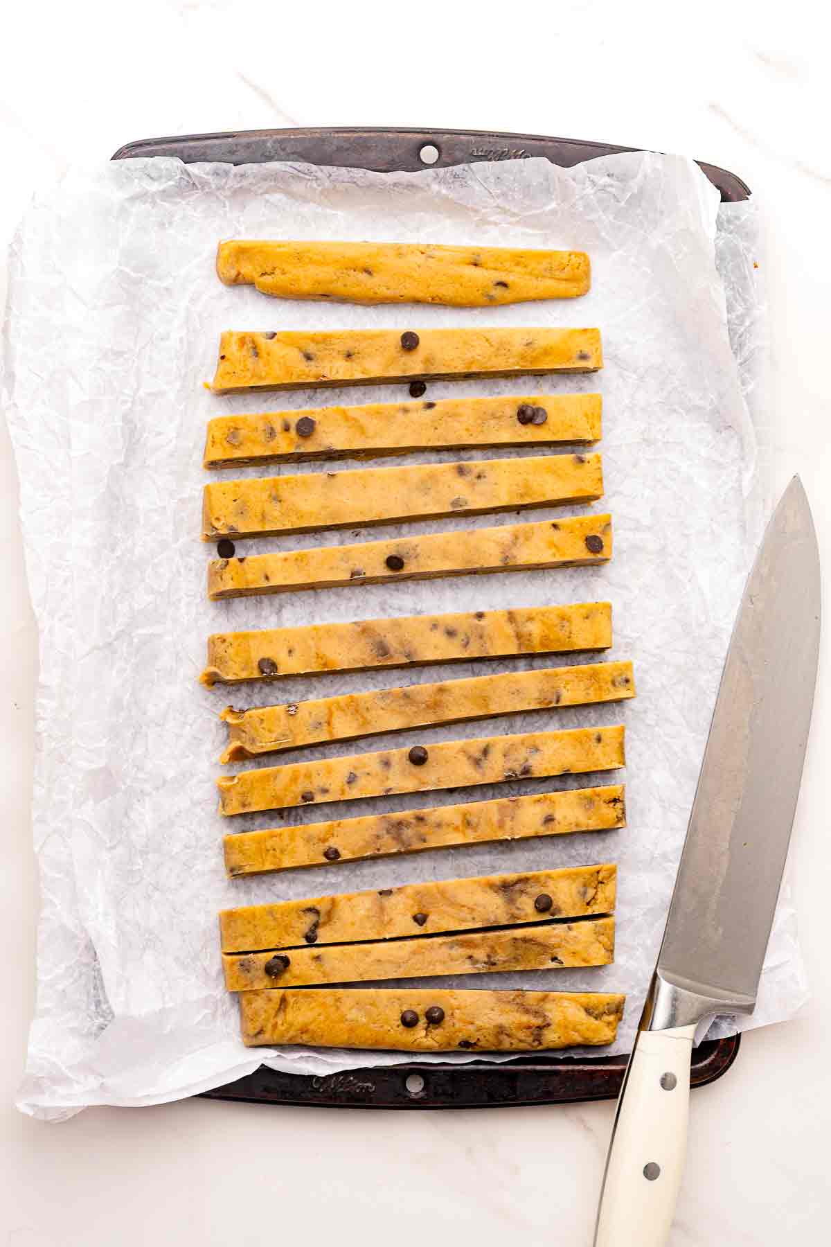 Cookie dough cut into thin cookie fry sticks on parchment paper