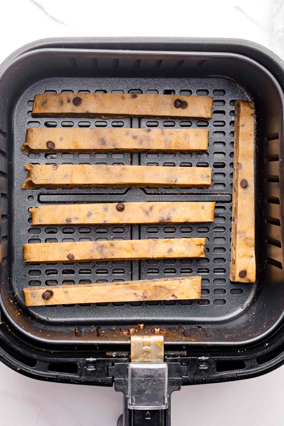 Uncooked cookie fries arranged in an air fryer basket