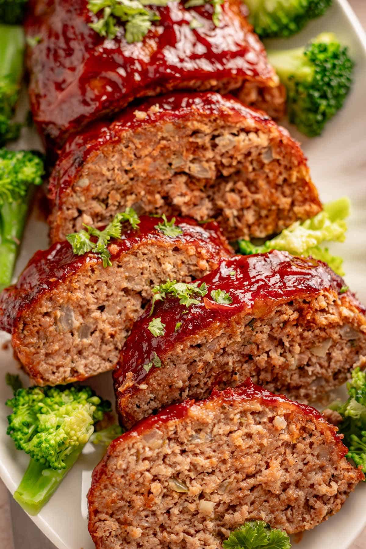 Glazed meatloaf slices with broccoli on a white plate