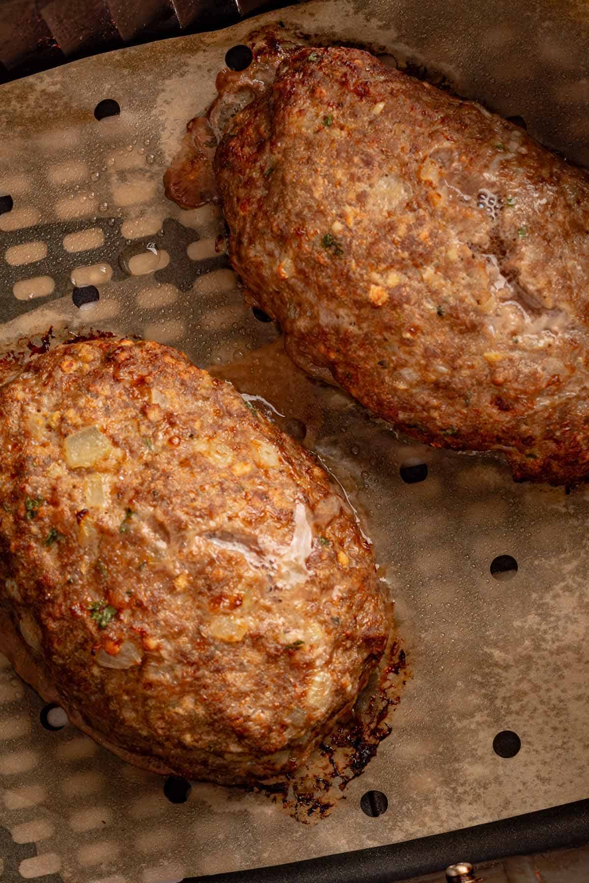 Air-fried meatloaves with browned edges in an air fryer basket