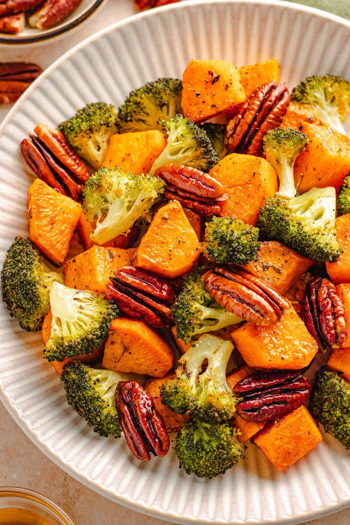 Roasted broccoli, sweet potatoes, and pecans served in a white bowl