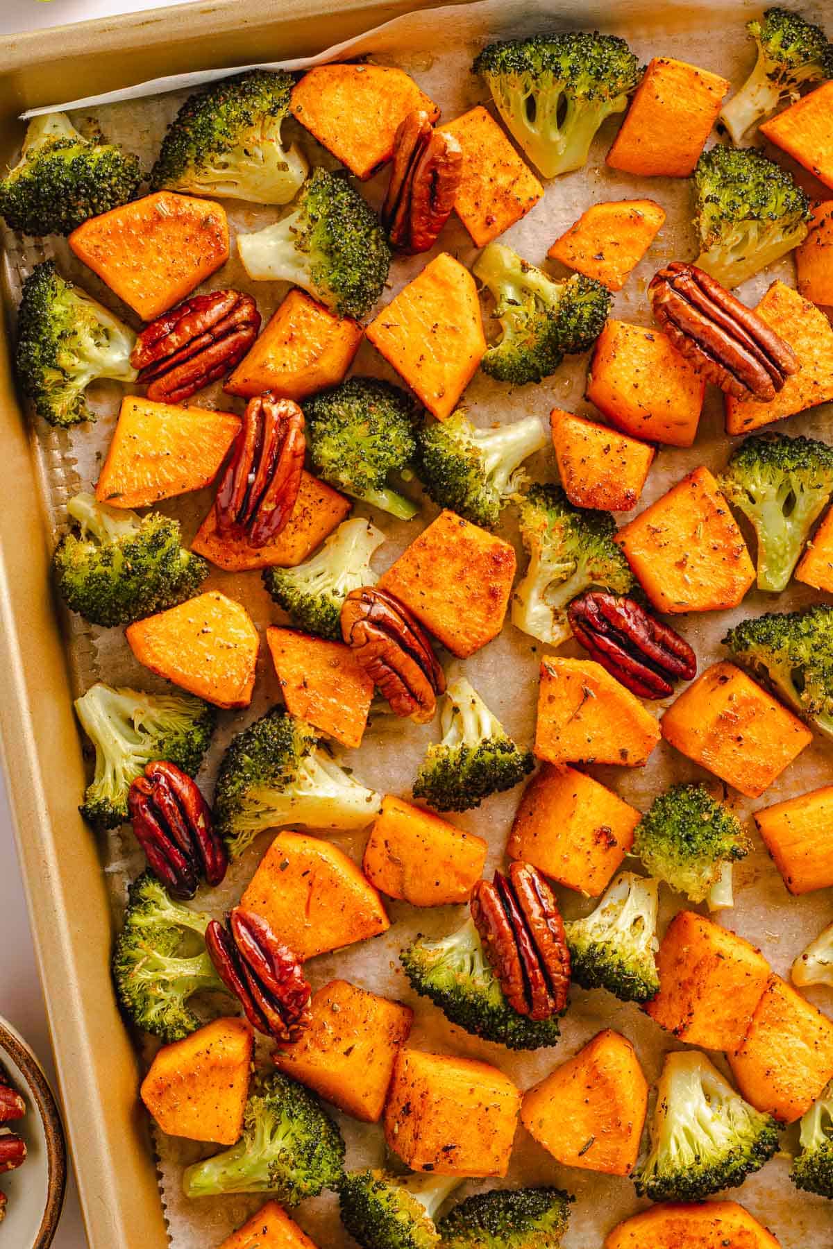 Roasted broccoli and sweet potatoes with pecans on a sheet pan