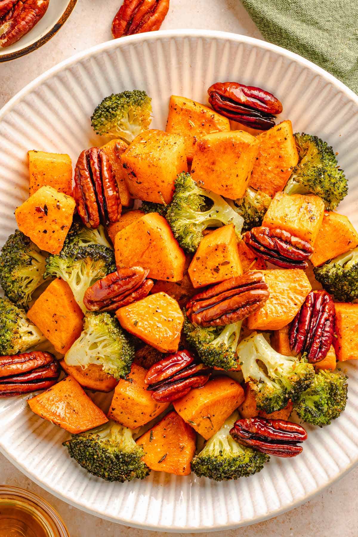 Roasted broccoli, sweet potatoes, and pecans served in a large bowl