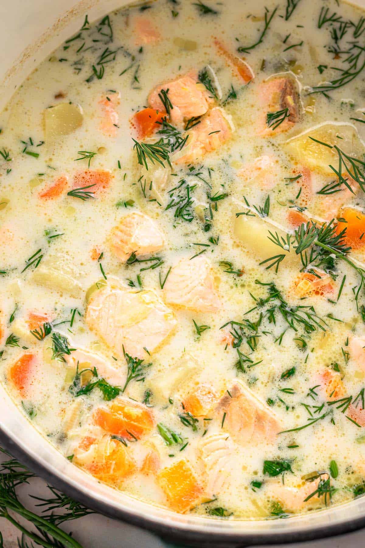 Close-up of creamy Finnish salmon soup with potatoes, carrots, and fresh dill.
