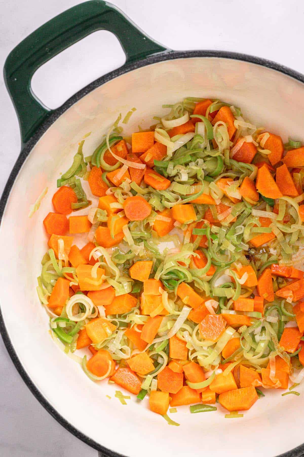 Sliced leeks and carrots cooking in butter for Finnish salmon soup.