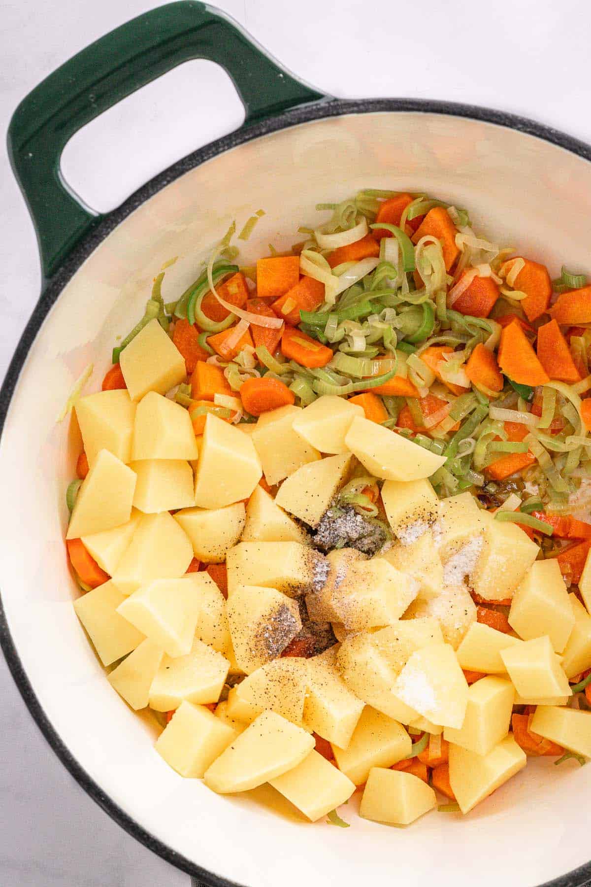 Potatoes, seasonings, and leeks added to carrots before cooking the soup.