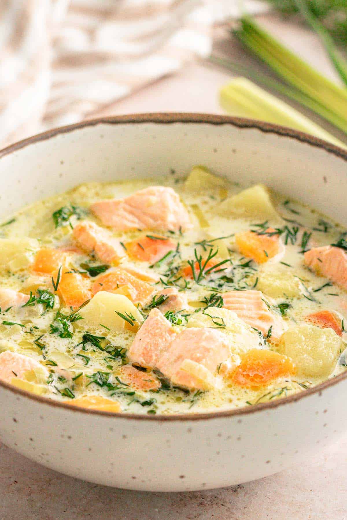 Overhead view of creamy Lohikeitto with salmon, potatoes, carrots, and dill.