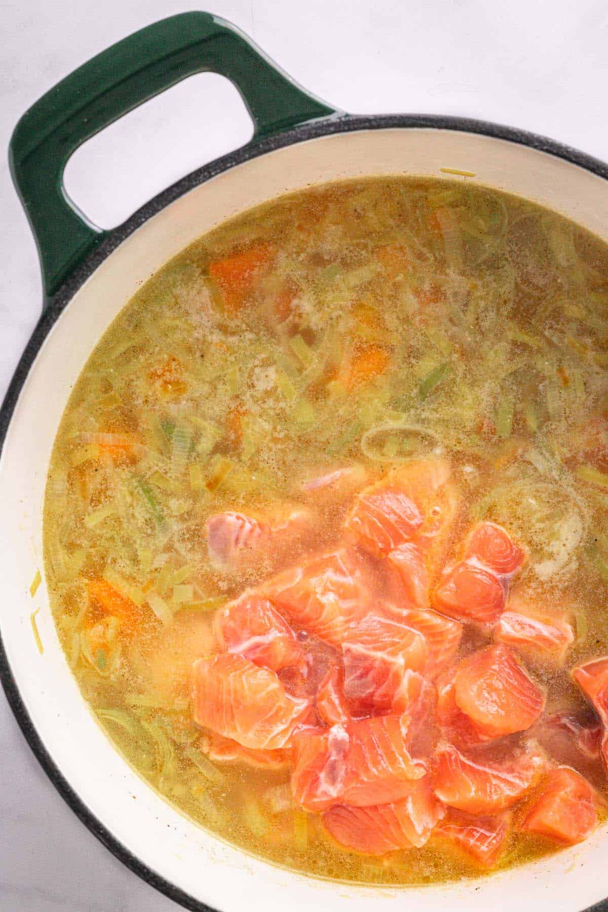 Raw salmon pieces added to simmering Finnish salmon soup.