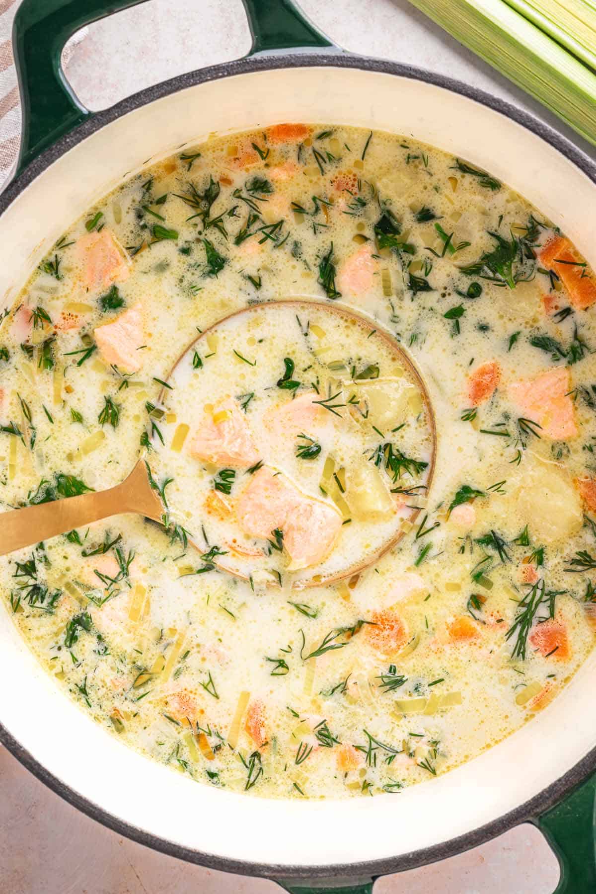 Creamy Lohikeitto (Finnish salmon soup) in a Dutch oven with a ladle.