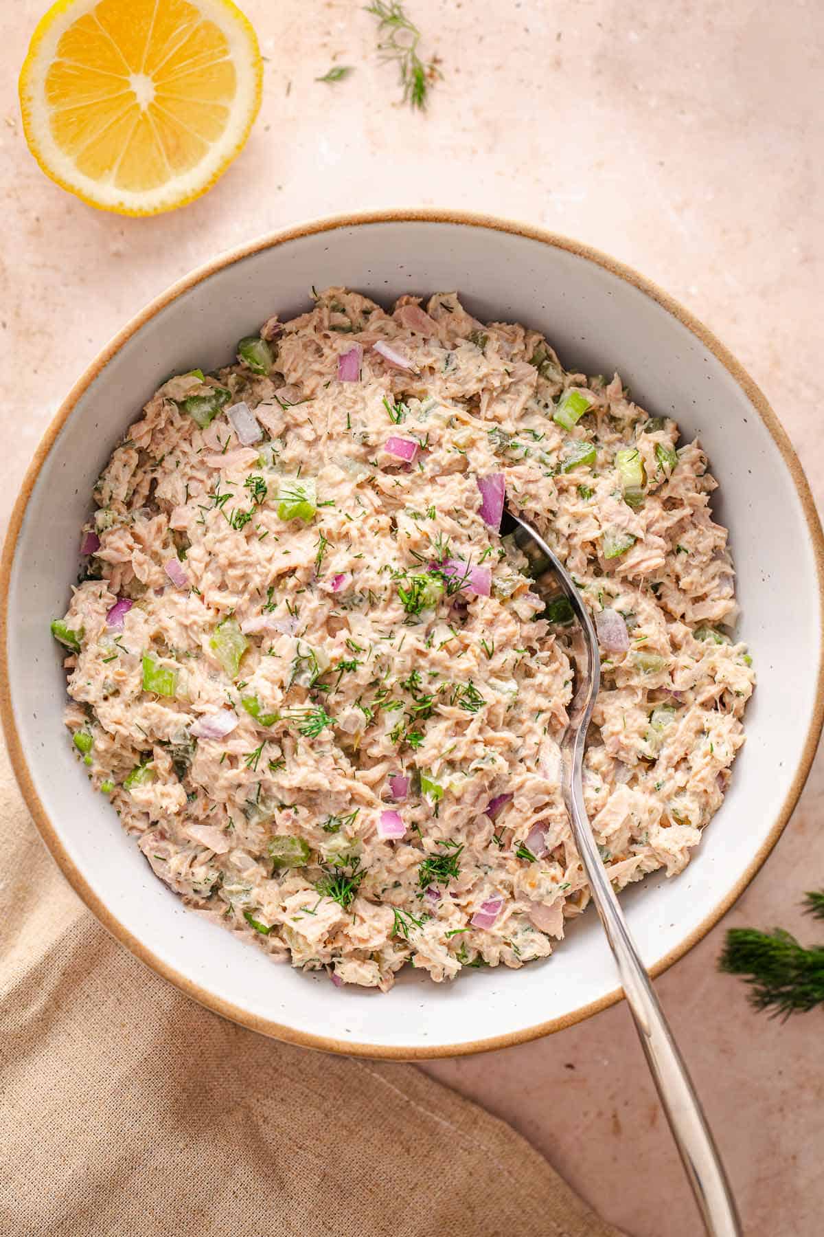 Bowl of creamy tuna salad with celery, red onion, pickles, and fresh dill