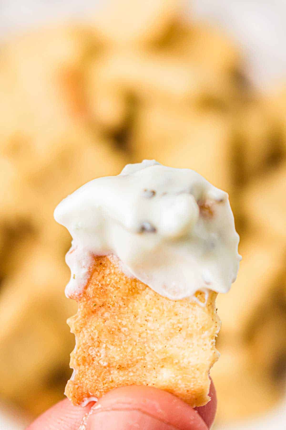 Herb sourdough cracker dipped in creamy vegetable dip
