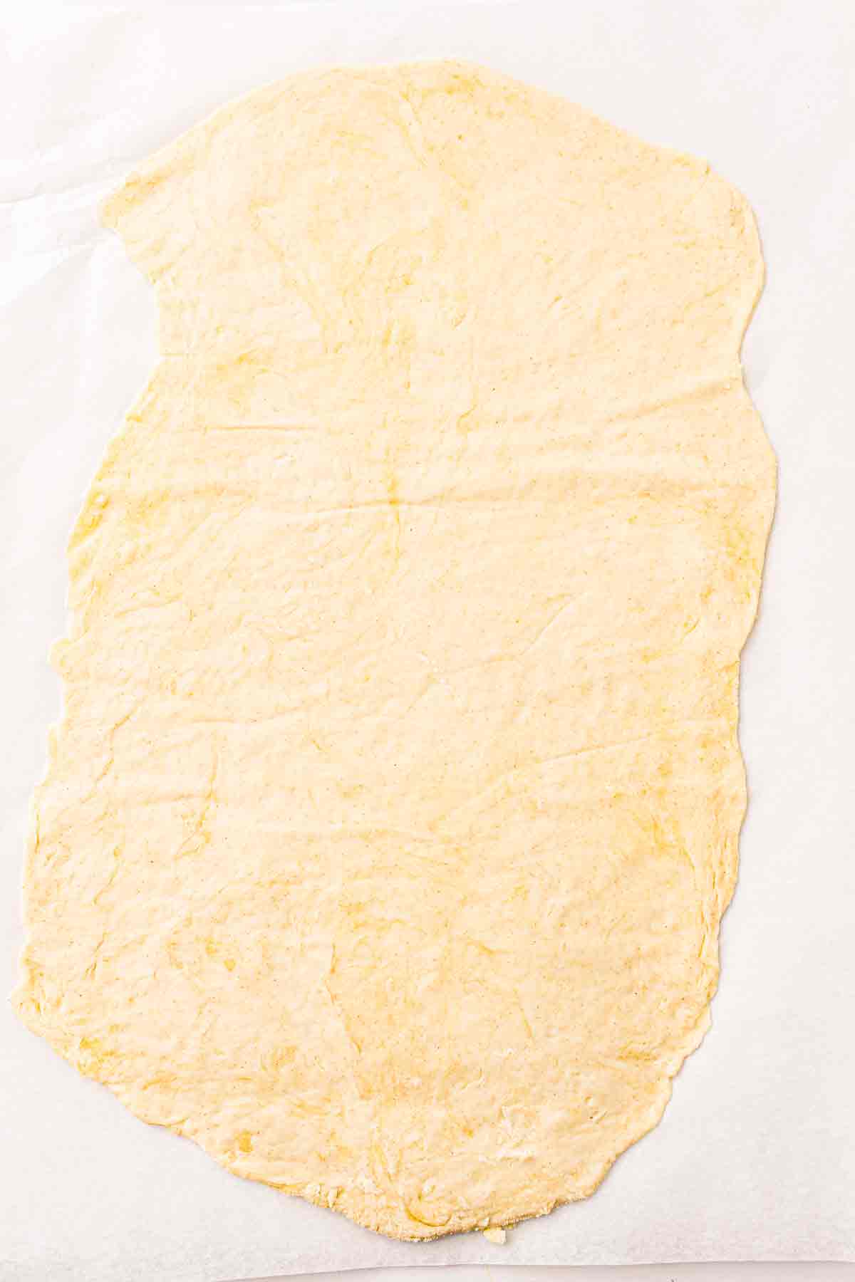 Thinly rolled sourdough cracker dough on parchment paper