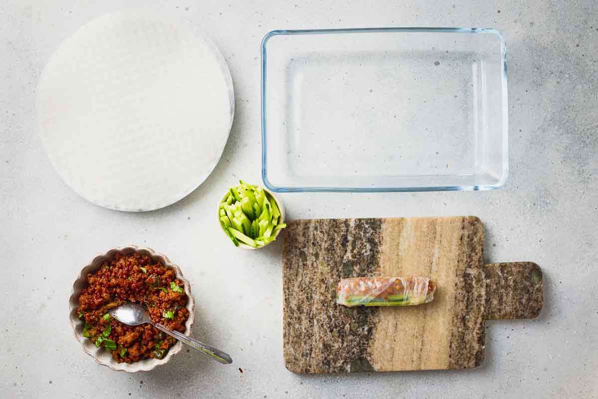 Ground beef spring roll rolled and sealed on a cutting board before serving.