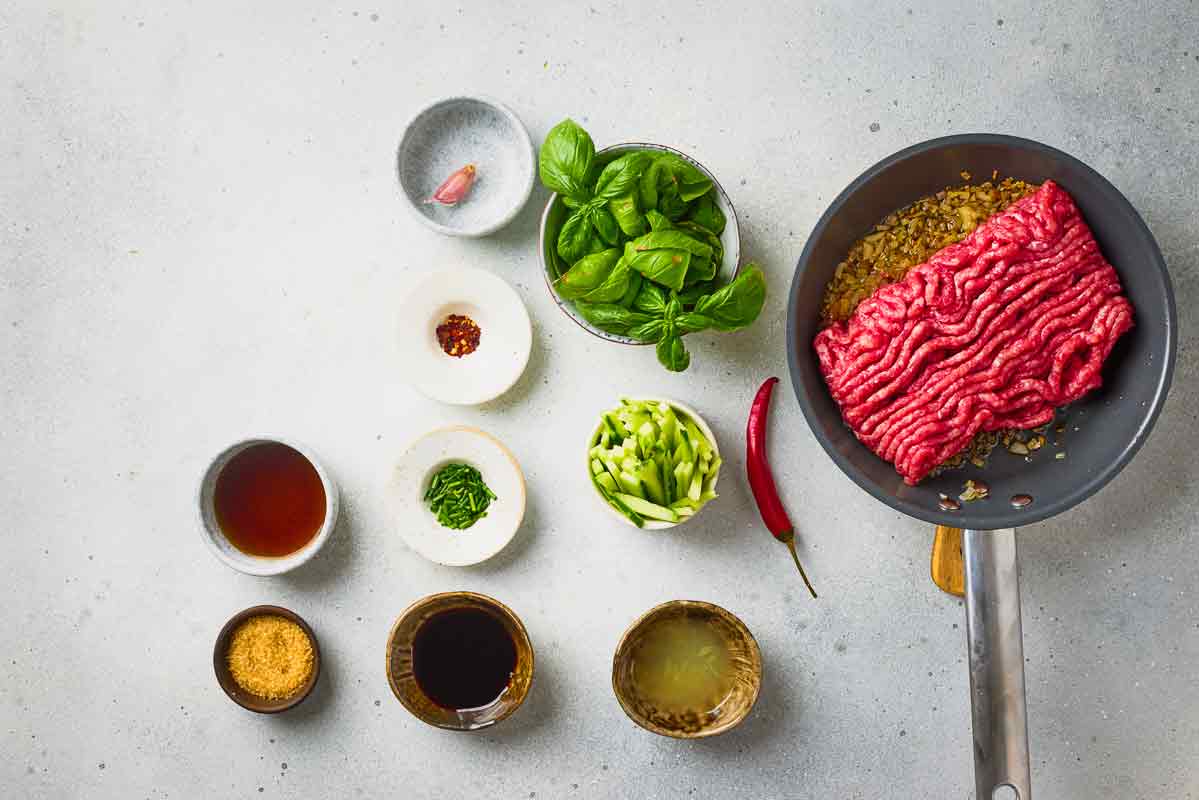 Ground beef added to a skillet with sautéed garlic and shallots.