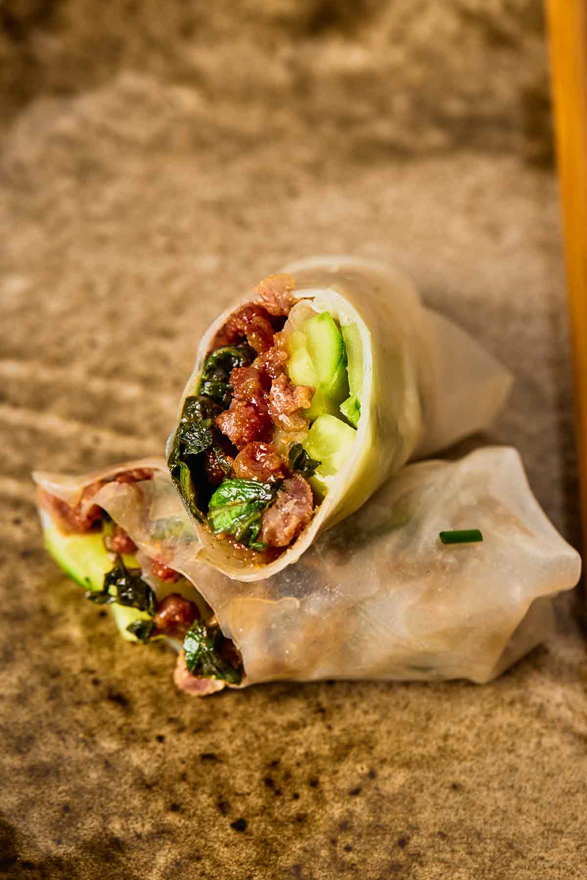 Close-up of a sliced ground beef spring roll with cucumber and Thai basil filling.