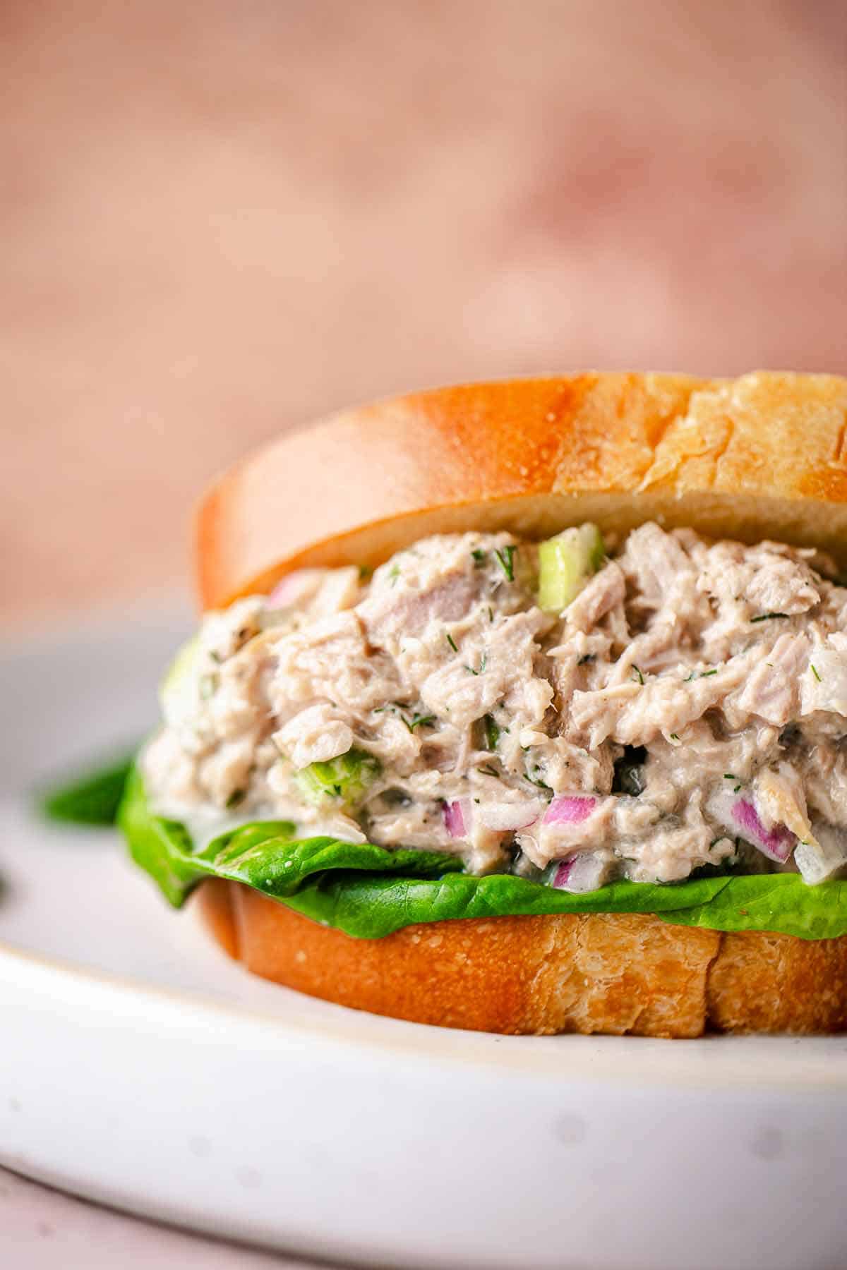 Creamy tuna salad sandwich with lettuce, celery, red onion, and dill