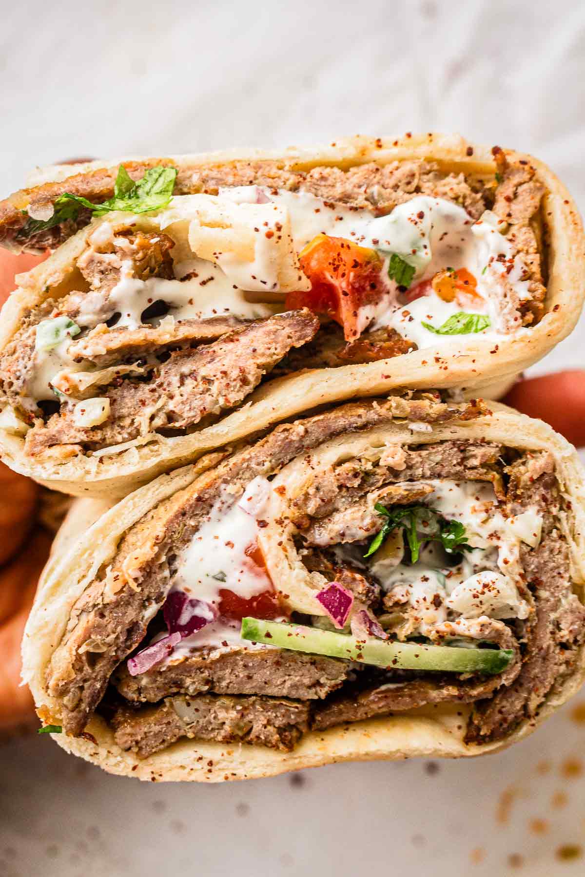 Homemade kebab wrap filled with sliced kebab meat, vegetables, and garlic sauce
