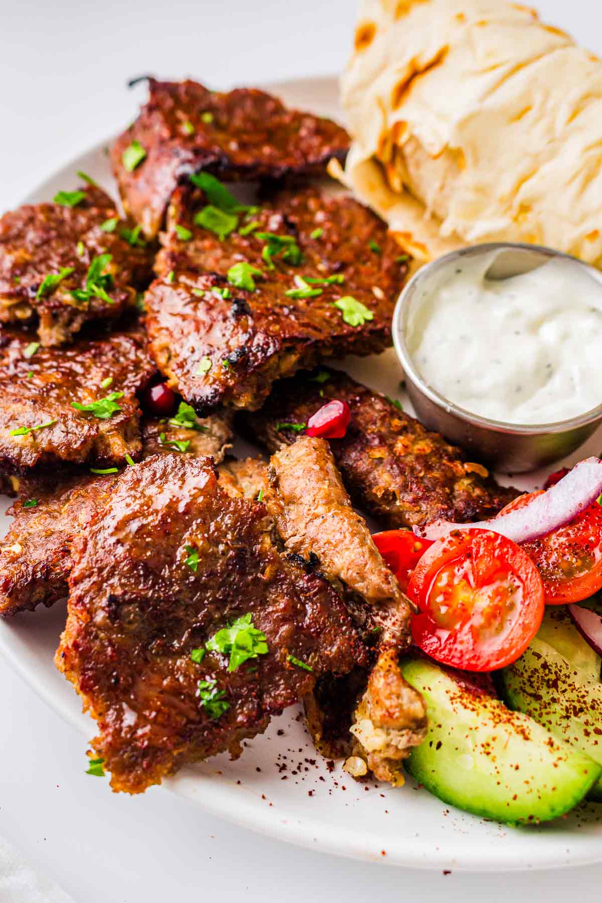 Cooked doner kebab meat served with pita, garlic sauce, cucumber, tomatoes, and onion
