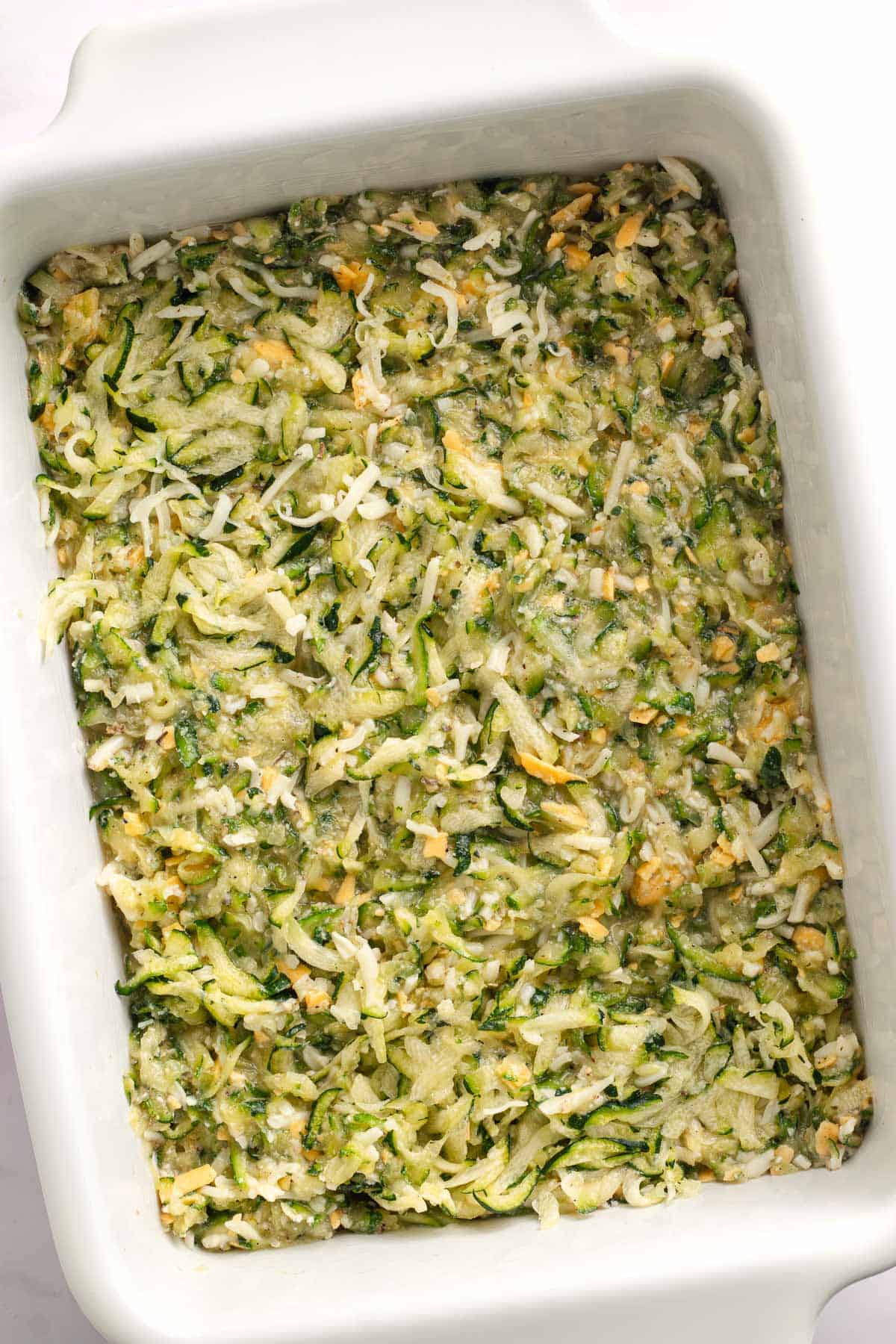Zucchini casserole filling spread evenly in a greased baking dish before baking