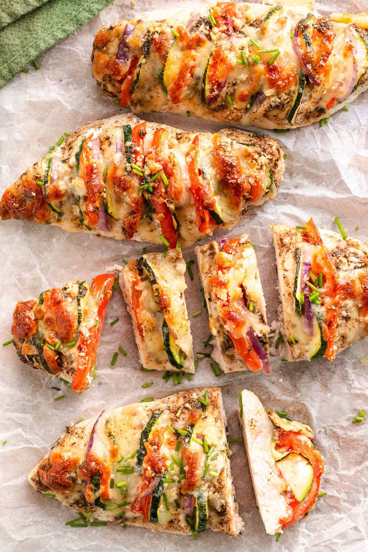 Baked Mediterranean hasselback chicken on parchment with sliced pieces for serving