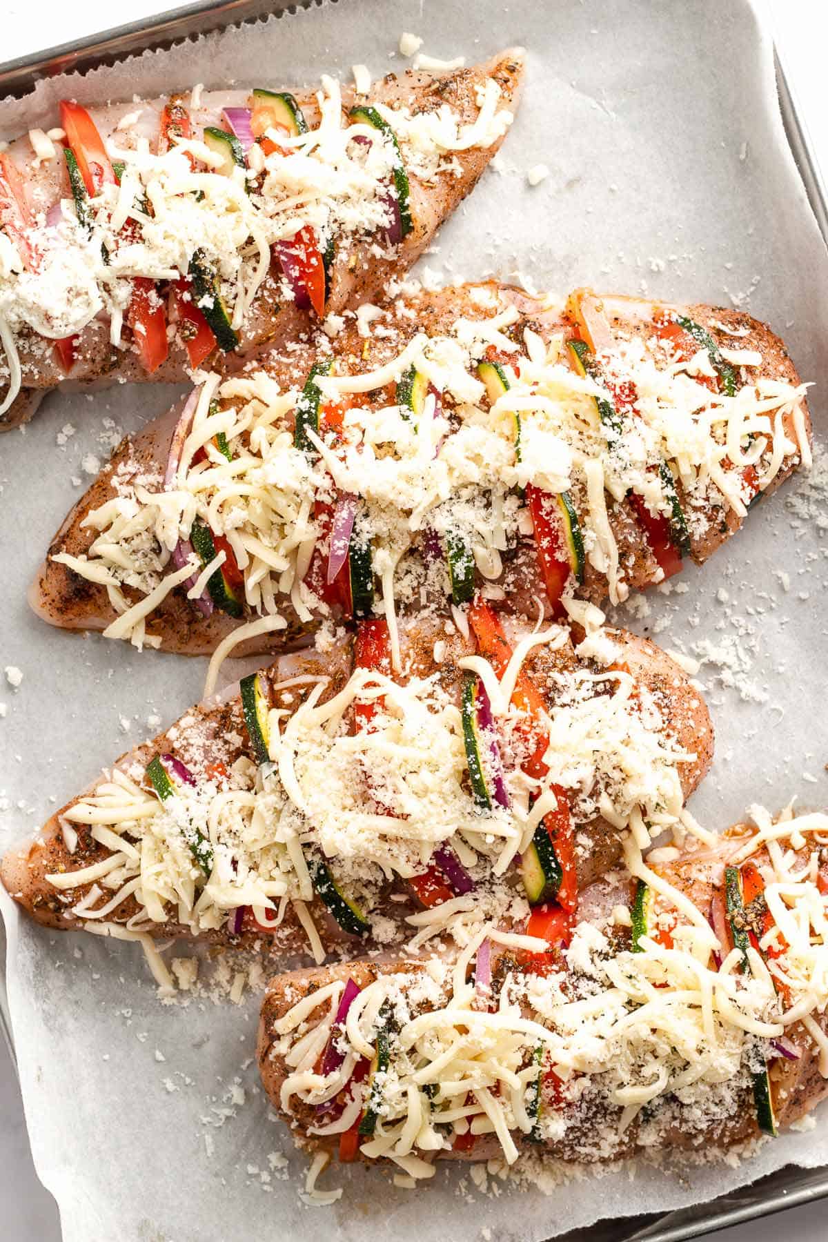 Stuffed chicken breasts topped with mozzarella and Parmesan before baking
