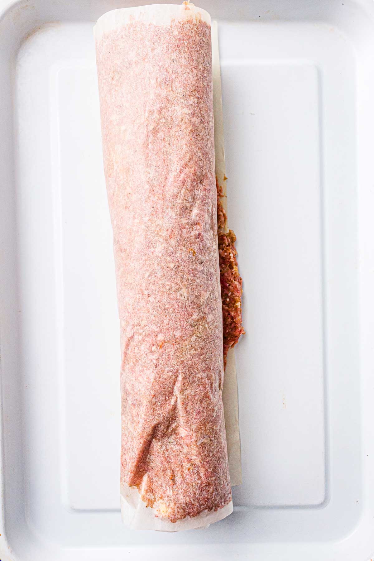 Raw kebab meat rolled into a tight log on a baking tray