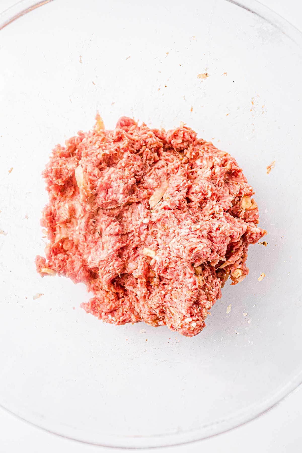 Ground meat mixture fully combined with onion, garlic, and seasonings