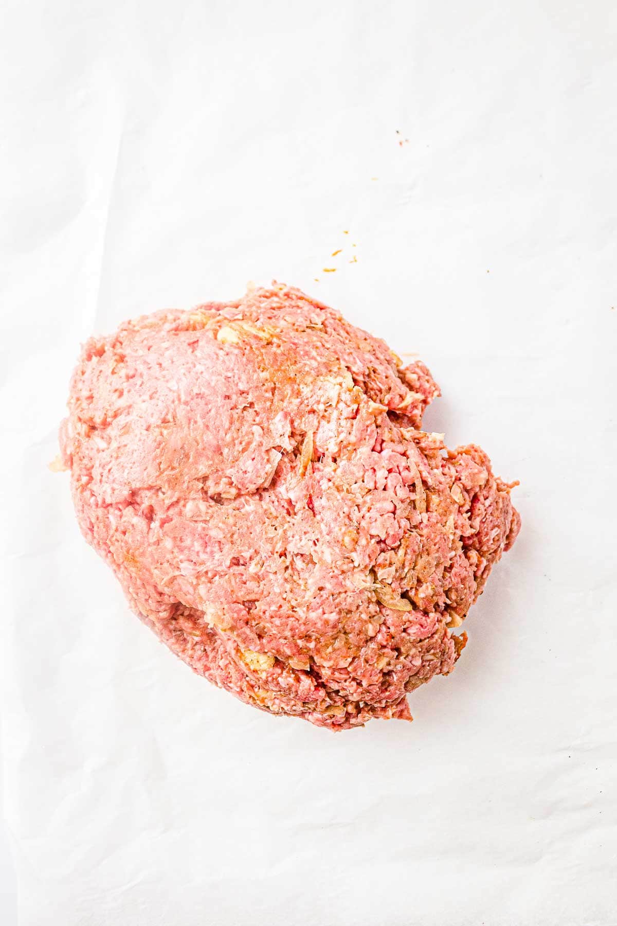 Seasoned ground meat placed on parchment paper before shaping