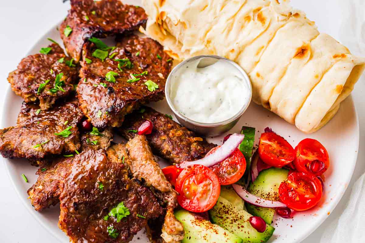 Homemade doner kebab served with flatbread, garlic sauce, cucumber, and tomatoes