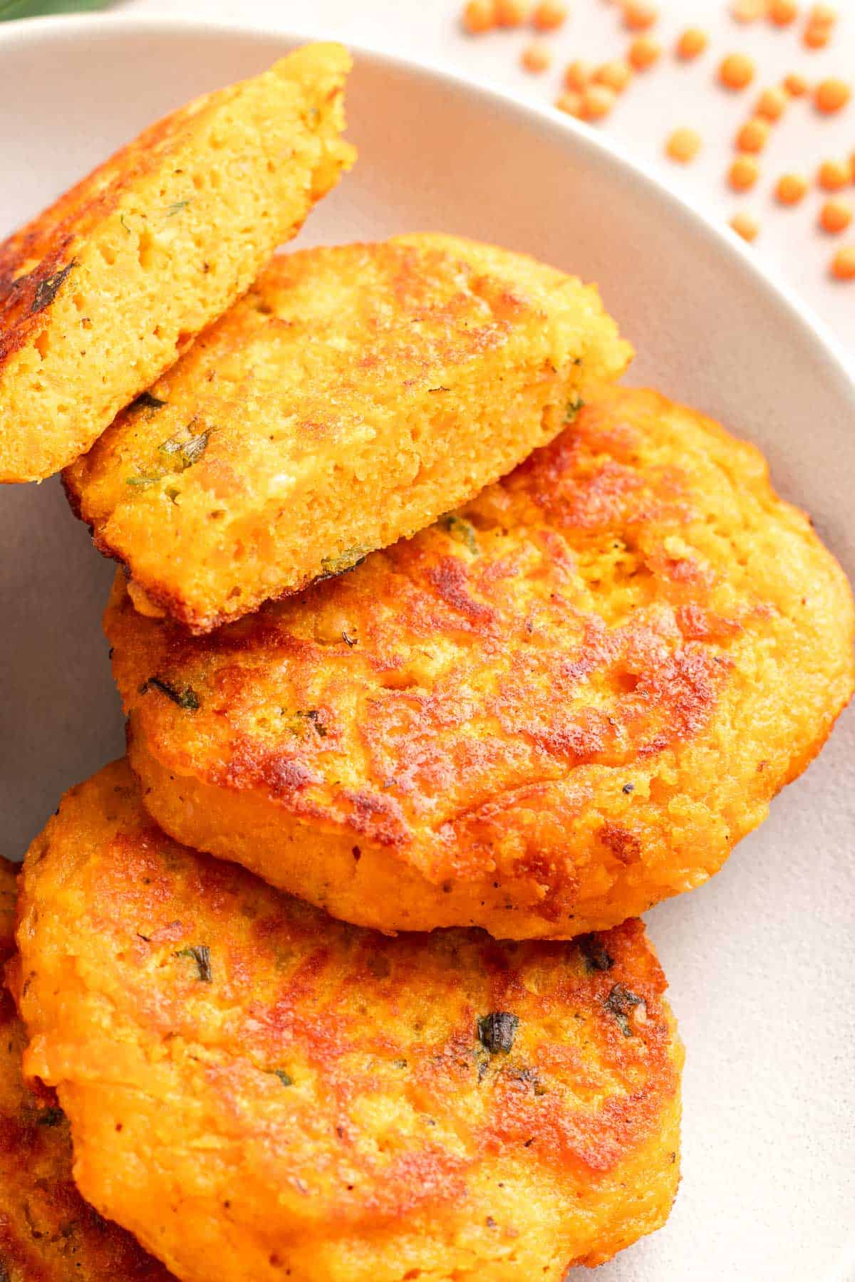 Cooked red lentil veggie cakes stacked on a plate