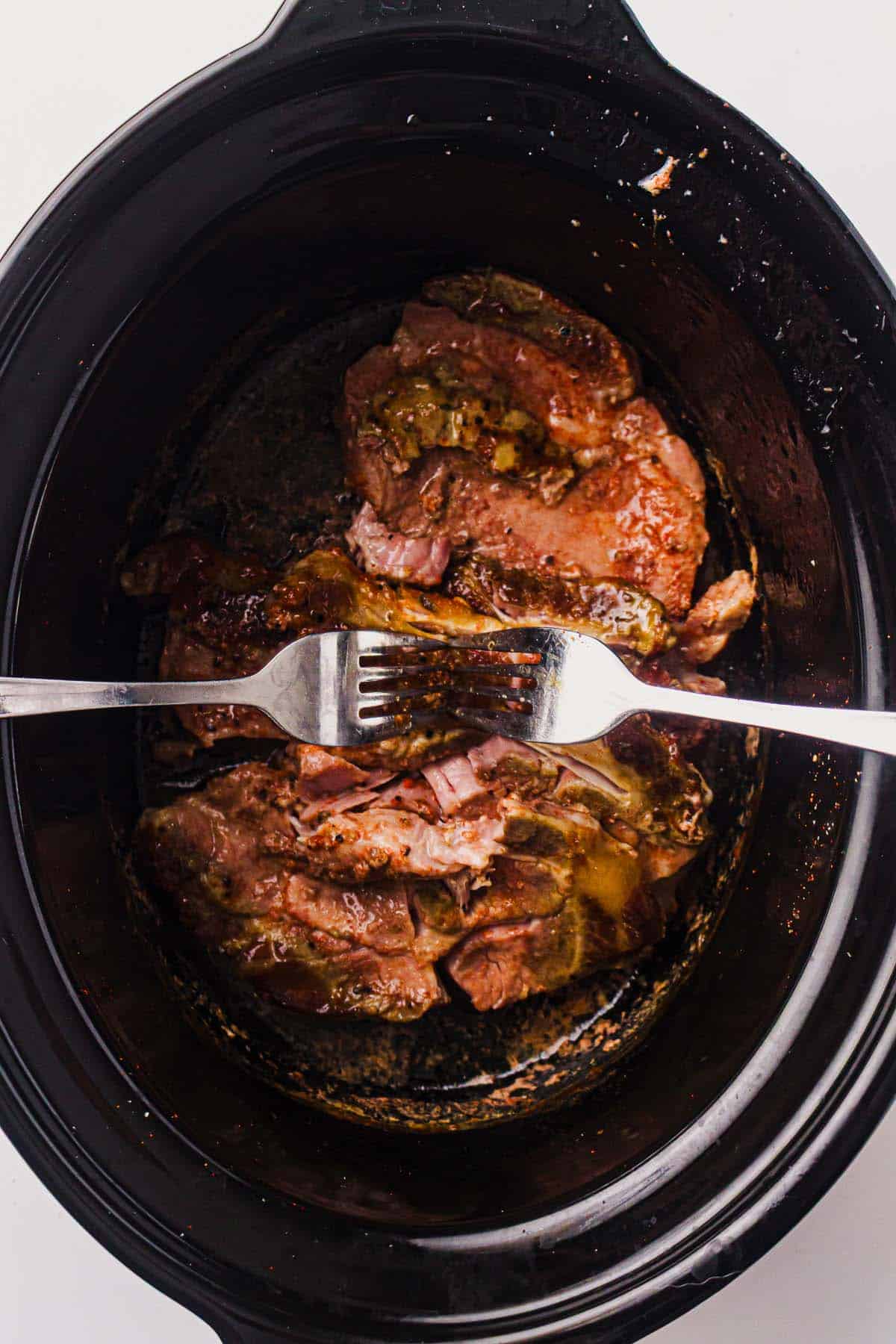 Cooked pork shoulder tested for tenderness with two forks