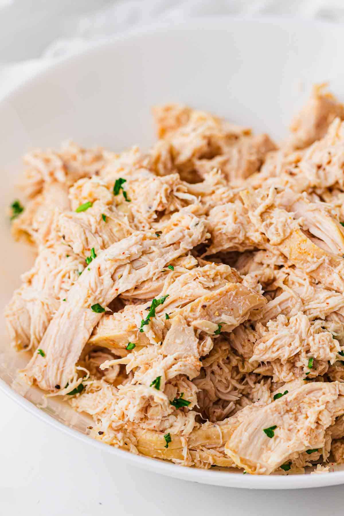 Shredded chicken mixed with cooking juices in a slow cooker.