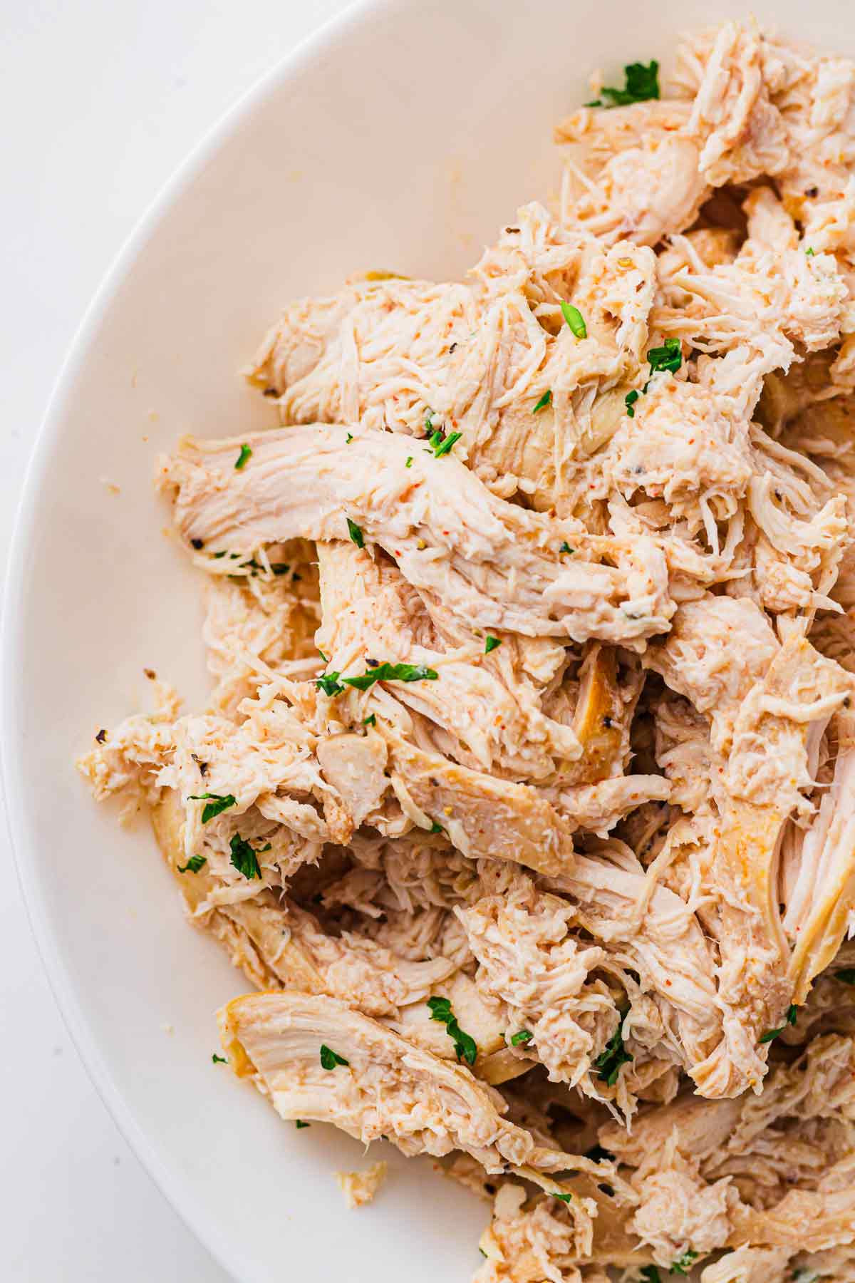 Close-up of juicy slow cooker pulled chicken in a serving bowl.