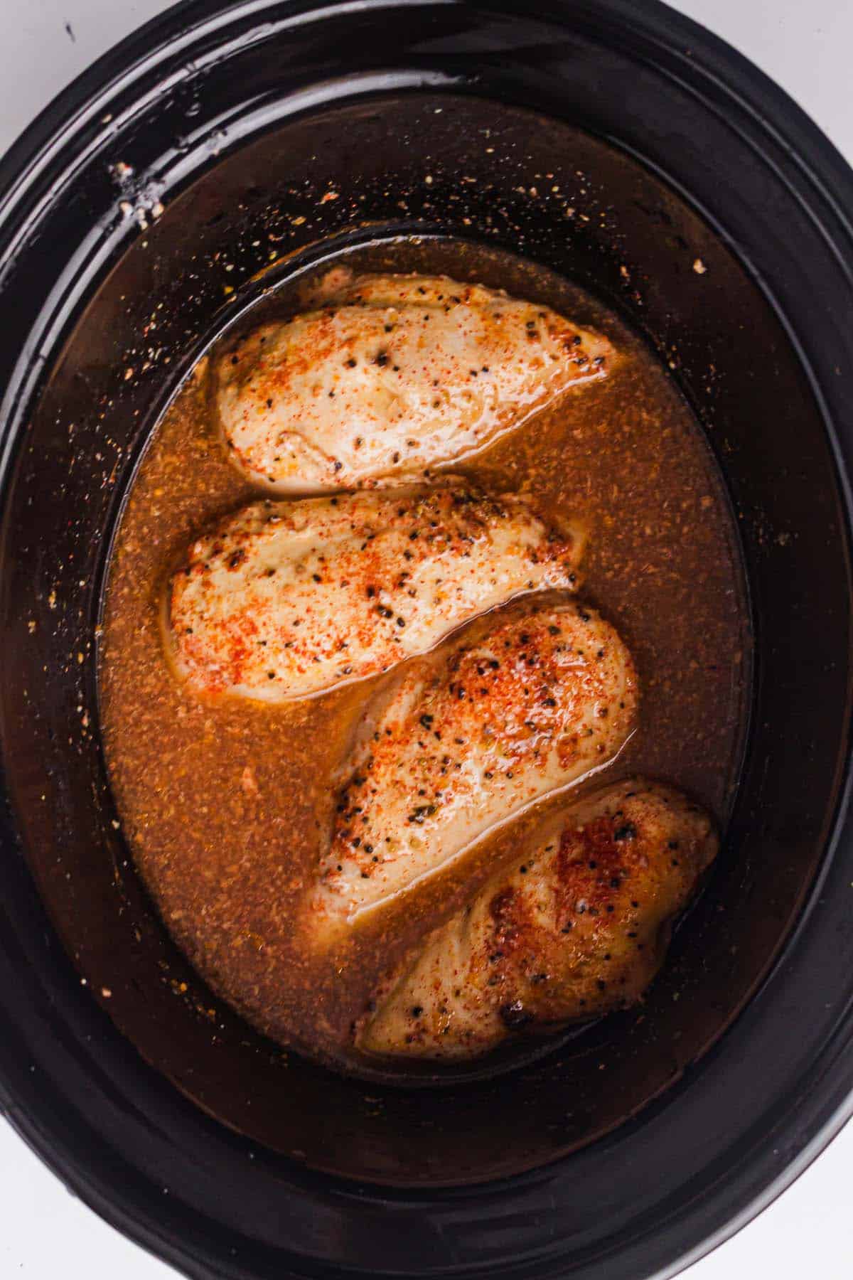 Cooked chicken breasts in a slow cooker ready to be shredded.
