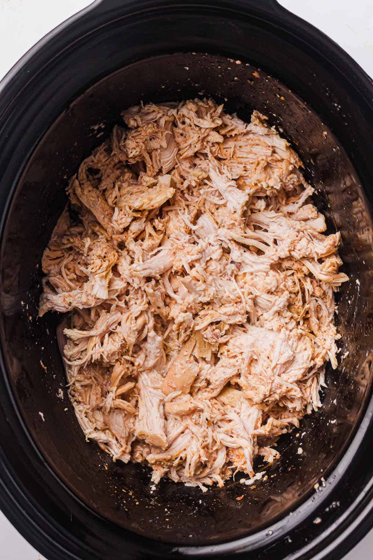 Bowl filled with tender slow cooker pulled chicken.