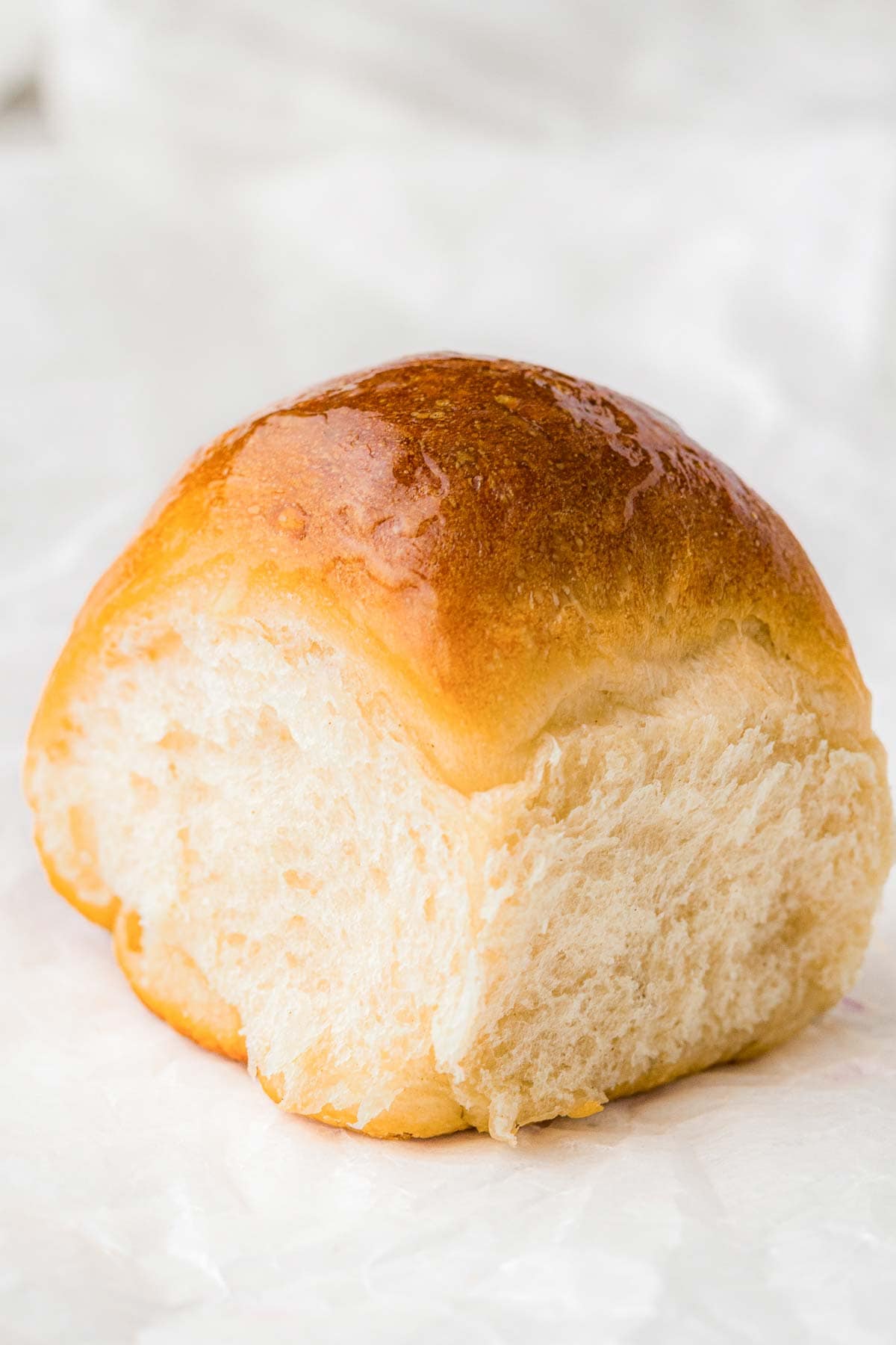 Single fluffy homemade dinner roll with a golden brown crust.