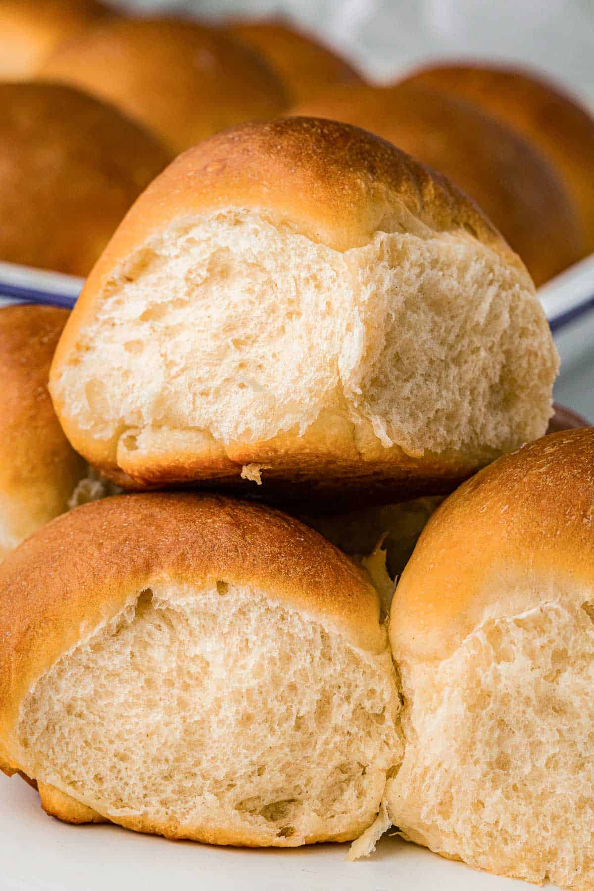 Stack of fluffy homemade dinner rolls showing their soft interior.