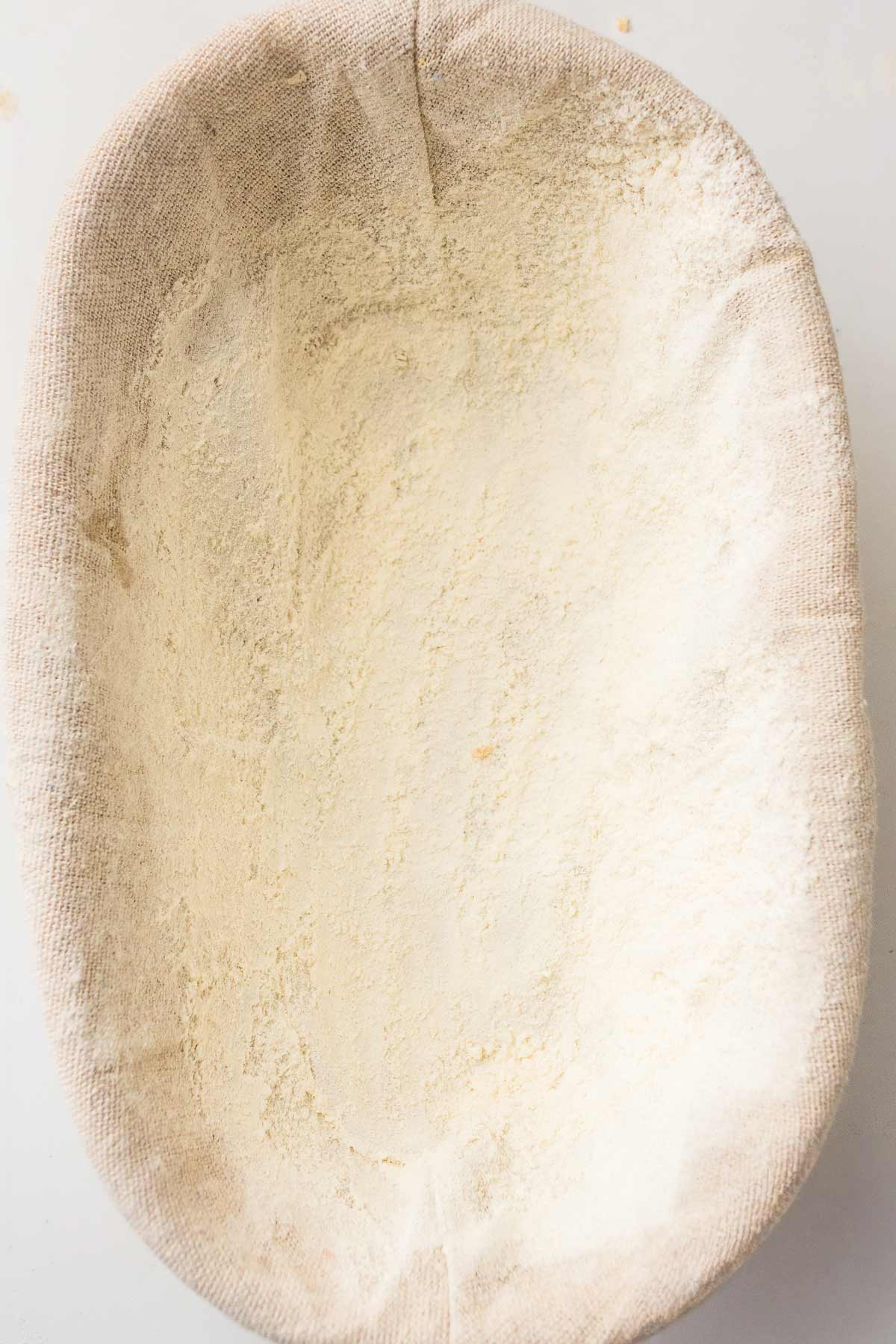 Shaped sourdough dough resting in a floured proofing basket